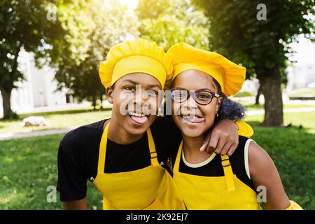 African children cooks in chefs hat and yellow uniforms grimacing and  showing tongue each others. African teenager and black girl have fun and  cook fo Stock Photo - Alamy