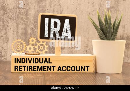On a bright blue background, light wooden blocks and cubes with the text IRA Individual Retirement Account. Stock Photo