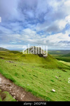 In the summertime along the pathway with beautiful green grass covered scenery,blue sky and summer clouds and views towards Portree. Stock Photo