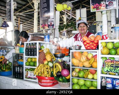 CUZCO, PERU - JAN 18, 2015: friendly local woman sells fresh juices to tourists at the central market in Cuzco, Peru. Beside local fruit she also offe Stock Photo