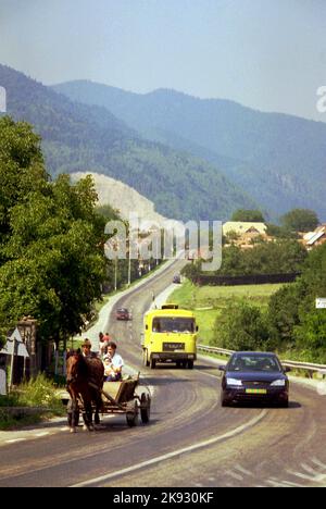 Harghita County, Romania, approx. 2000. Family with small child riding in a horse-pulled wagon on a busy country road. Stock Photo