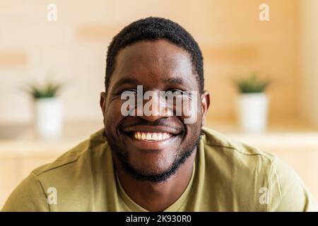 portrait of cheerful happy young man with in casual white t-shirt at home Stock Photo