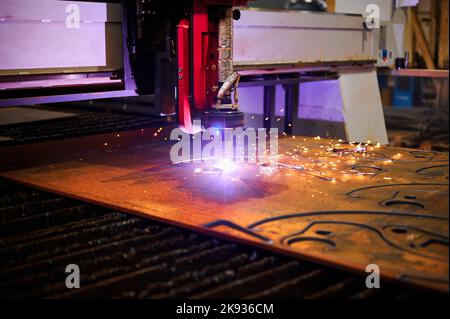 Plasma cutting of metal plate with flying sparks in workshop Stock Photo