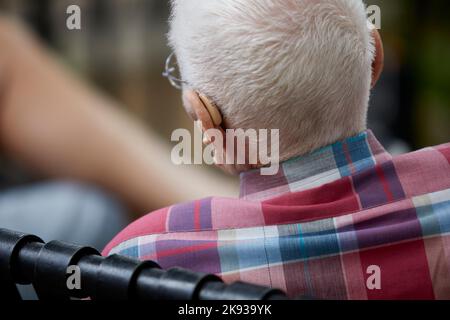 White Haired elderly man wearing hearing aids with shallow depth of field Stock Photo