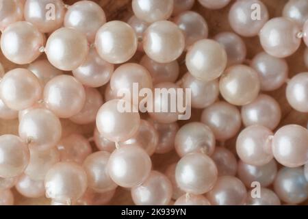 close-up of light pink color string of pearls, taken in soft focus, full frame blurry background texture Stock Photo