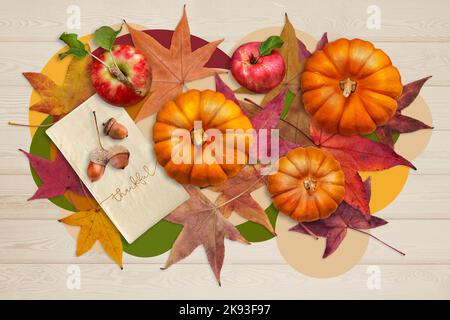 Apples, pumpkins, acorns on napkin that says Thankful, and fallen leaves on light wood background. Top view. Thanksgiving autumn background. Stock Photo