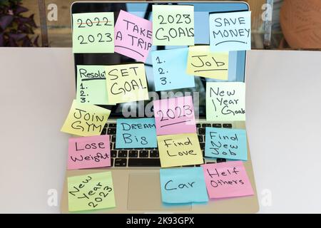 Colorful sticky notes with new year goals and resolutions pasted on a laptop Stock Photo