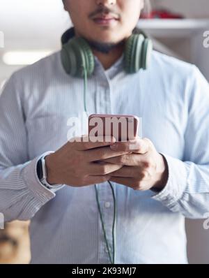 Social media is the voice of the millennial. a young businessman using a smartphone in a modern office. Stock Photo