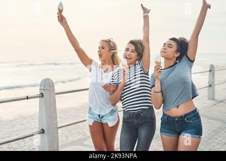 Its ice cream season. three friends eating ice while out on the promenade. Stock Photo