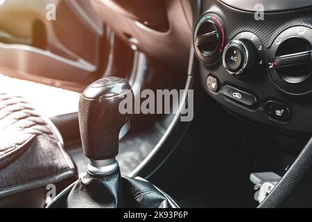 The shift knob of a manual transmission in the black interior of a car Stock Photo