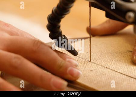Close-up on the process of sawing fiberboard on a scroll saw with a blower Stock Photo