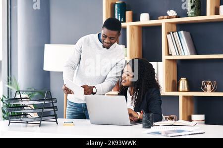 With teamwork comes progress. a young businessman and businesswoman using a digital tablet and laptop in a modern office. Stock Photo