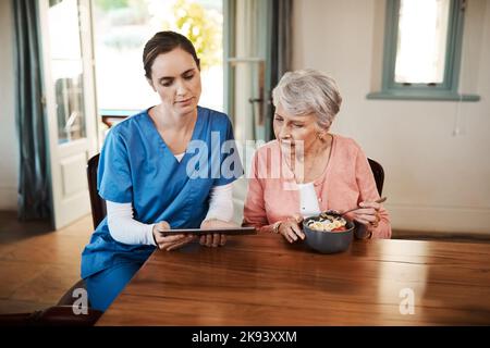 And you can check up on the news here. a young nurse and senior woman using a digital tablet at breakfast time in a nursing home. Stock Photo