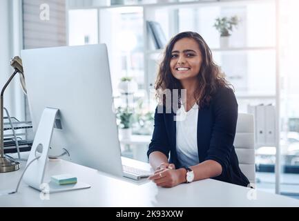 Just another busy but successful day at work. Portrait of a young businesswoman working on a computer in an office. Stock Photo