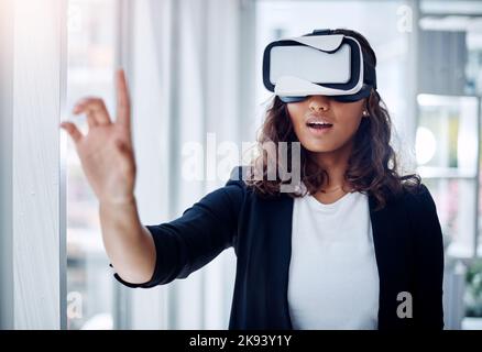The possibilities will amaze you. a young businesswoman wearing a VR headset in an office. Stock Photo