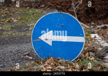 left turn sign stands on the road in autumn without a pillar on the ground, road sign Stock Photo