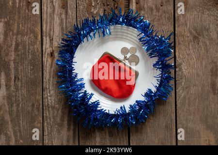 red wallet lies on a white plate decorated New Year's colored ribbon on a wooden background close-up, New Year's decor Stock Photo