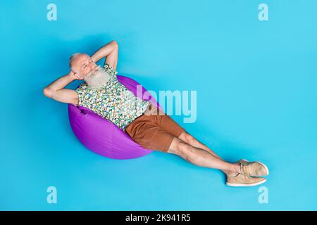 Full body high angle view portrait of peaceful sleeping aged man isolated on blue color background Stock Photo
