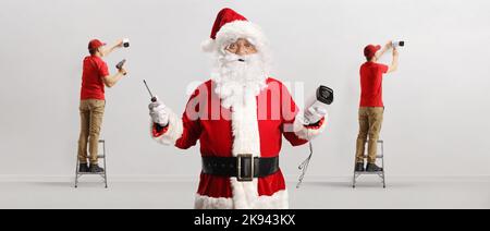 Team of technicians installing security cameras and santa claus holding a cctv camera and a screwdriver Stock Photo