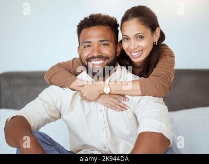 Couple, smile and sofa for portrait with back, woman or love in living room while home together. Black woman, man and happy for embrace, care or hug Stock Photo