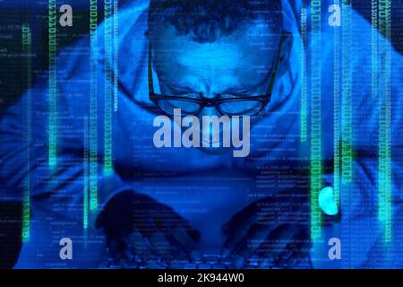 Hes a mastermind when it comes to cyber crime. a young male hacker cracking a computer code in the dark. Stock Photo