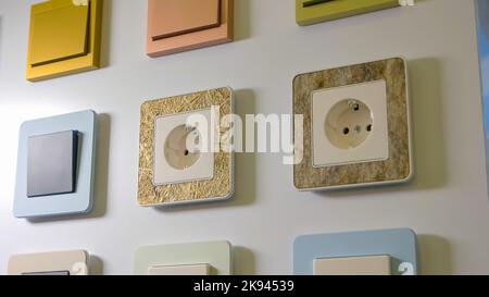 Various sockets and switches on the white wall. Electrical equipment store. Stock Photo