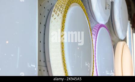 Close-up collection of ceiling chandeliers in the store. Many various round lights. Stock Photo