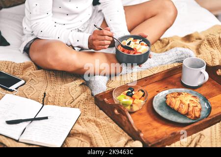 Get in my belly. an unrecognizable woman holding a bowl of oats while she has breakfast in bed at home. Stock Photo