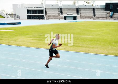 Preparing my body for the marathon. Full length shot of a handsome young athlete running a track field alone during an outdoor workout session. Stock Photo