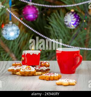 Cup of coffee, candle and a fir tree with Christmas ornaments on the background. Stock Photo