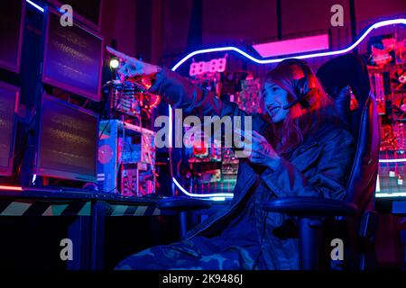 Woman wear gaming headphones playing esports games console gaming room, Gamer using joystick controller for race tournament plays online video game wi Stock Photo