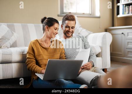 Lets check our credit score. a young couple using a laptop while relaxing at home. Stock Photo