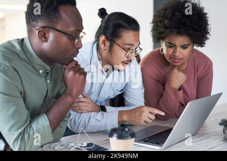 Theyre a powerhouse for productivity. a group of young businesspeople using a laptop in a modern office. Stock Photo