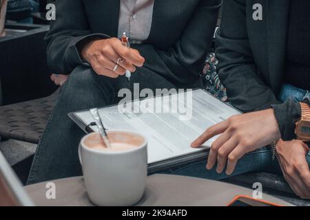 The hands of two females checking a list on their lap Stock Photo