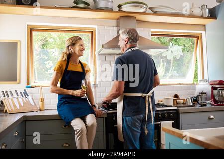 Retirement, senior couple and cooking in kitchen have discussion, talking or loving prepare meal together. Love, mature man and elderly woman is Stock Photo