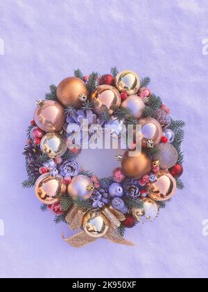 Christmas decorative wreath with pine cones, Christmas tree golden balls and ornaments on a textured background. Toned image in color Very peri Stock Photo