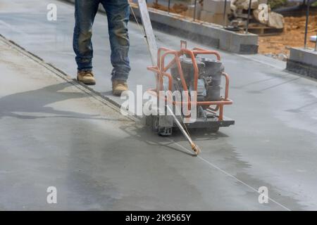 After foundation concrete has been poured in construction site, workers are using cutting machines to cut concrete for expansion foundation concrete Stock Photo