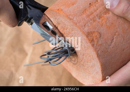 making a dispenser for nesting material for birds or squirrels, step 4: a handle in formed with the wire and the ends are cut, series picture 4/5 Stock Photo