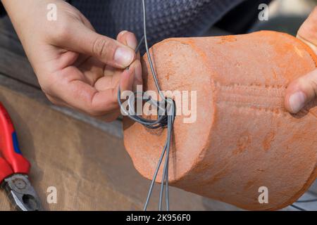 making a dispenser for nesting material for birds or squirrels, step 4: a handle in formed with the wire and the ends are cut, series picture 4/5 Stock Photo