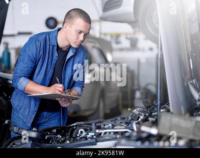 Car service, inspection and mechanic by car with clipboard checking engine. Technician, engineer and man working in garage or workshop writing notes Stock Photo