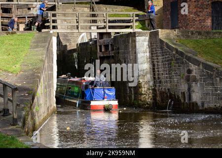 A barge (narrowboat, flat bottomed boat) enters the bottom lock of Five Rise Locks in Bingley, Yorkshire on the Leeds Liverpool Canal. Stock Photo