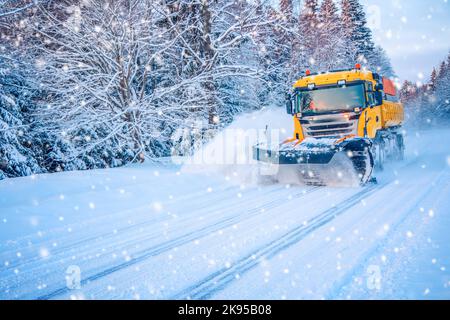 Snow plow truck cleaning road in snowstorm. Stock Photo