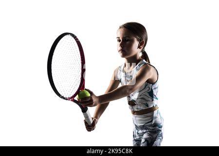 Young female tennis player silhouette. Little girl posing with racket and ball isolated on white background. Stock Photo