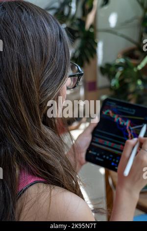 A closeup of a young female checking a graph on a tablet and digital pen Stock Photo
