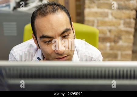 The Media Agency: Office Worker. A mature male business professional concentrating on his computer monitor screen. From a series of related images. Stock Photo