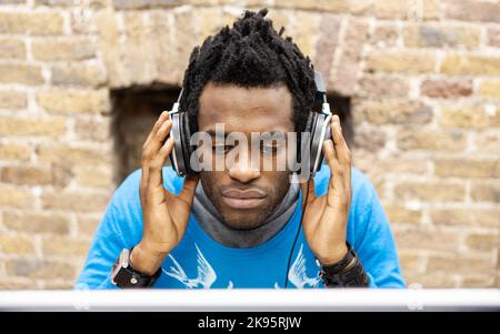 The Media Agency: Checking Levels. An audio engineer working at his desktop in a creative office environment. From a series of related images. Stock Photo