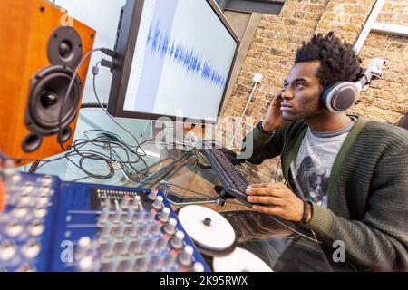 The Media Agency: Music Studio. An audio engineer at work editing in a recording studio - generic waveform on screen. From a series of related images. Stock Photo