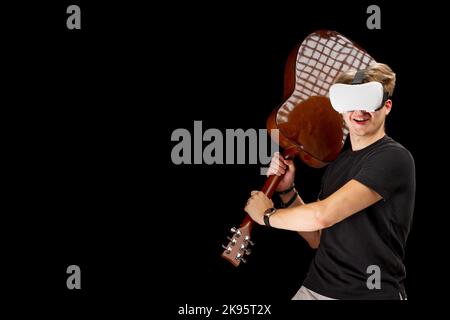 Man playing guitar game in virtual reality helmet. VR goggles, glasses, on black isolated background Stock Photo