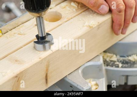 Carpenter drilling holes in the wood beam. wooden frame domestic house building Stock Photo