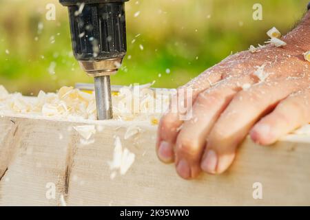 Carpenter drilling holes in the wood beam. wooden frame domestic house building Stock Photo